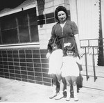 Annette and Margo Lederman, two Jewish children in hiding, pose with their rescuer, Clementine van Buggenhout, outside the cafe owned by the van Buggenhouts.