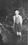 A Jewish boy who is living in hiding in Boissy-Saint-Leger, France, poses outside in front of  stone house.
