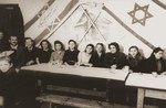 A group of young people pose in a "culture hall" beneath Jewish flags.