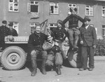 American military photographer Fred Frater poses with Russian soldiers in front of a jeep at their military base in Germany.
