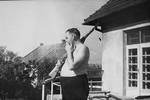 Commandant Amon Goeth stands with his rifle on the balcony of his villa in the Plaszow concentration camp.