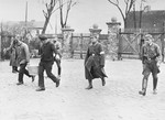 SA guards oversee prisoners who are carrying a tub near the entrance to the Oranienburg concentration camp.