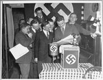 Paul Manger reads a newspaper article announcing Hitler's appointment as German Chancellor to fellow  members of the Nazi party at a celebration in New York.