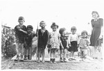 A group of Jewish preschoolers pose outside with their teacher at the Schlachtensee displaced persons camp.