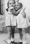 Close-up portrait of three-year-old Basia Israel hugging another young girl in the Krakow ghetto.