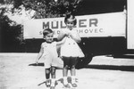 Portrait of the donor's niece and nephew, Agnes and George Muller in front of a truck bearing the name of their family's firm in Sered, Czechoslovakia.