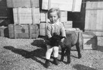 Portrait of the donor's son, Heinrich Muller with a black sheep in the courtyard behind their home and business in Hlohovec, Czechoslovakia.