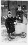 Two young children play outside next to a baby carriage in Bogdan, Transcarpathia.