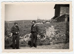 Two Jewish youth in hiding stand in the countryside near Treve.
