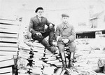 Isaac Ejber and Jacob Rajs sit on a wood pile at a sawmill near the Wlodawa ghetto.