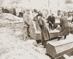 Under the direction of American soldiers, German civilians from Wilhelmshoehe lower a coffin into a grave.