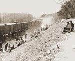 Survivors rest on an embankment next to a stopped train.
