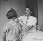 OSE relief worker Margot Stein gives a medical examination to a child at the Hotel Bompard internment camp.
