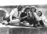 A group of Jewish girl scouts living at the Moissac children's home, play recorders on a riverbank.