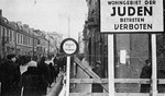 Postcard from the Lodz ghetto showing the entrance and a sign forbidding entrance to non-Jews to the ghetto.