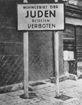 An entrance into the Lodz ghetto with a sign that reads:  "Jewish residential district: Entrance Forbidden."