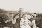 Bernhard and Sonja Schadur Goldstein with their daughter Evgenia sitting in a field.