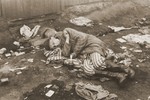 Having just eaten a tin of canned food given to him by British troops, and wearing a newly acquired pair of boots, a survivor in Bergen-Belsen sleeps on a pile of prisoners' uniforms.