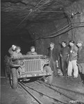 Two U.S. combat photographers from the 167th Signal Photo Company are greeted by four French miners during their investigation of the Burca iron mine that was thought to have been the site of a German bomb factory.
