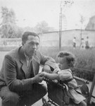A Jewish father crouches next to his young daughter in a stroller.