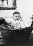 A young Jewish boy sits outside in a wicker basket in Osijek, Croatia.