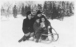 A Jewish family poses outside in the snow on a sled.