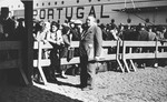 Albert Nussbaum, Director of Transmigration for the American Joint Distribution Committee, poses in the port of Lisbon in front of a wooden fence that cordons off the Jewish refugees who are waiting to board the SS Mouzinho.