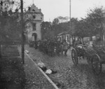 A column of Jews walks behind a wagon on a cobblestone street during a deportation action in the Wisznice ghetto.