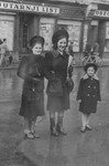 Two Jewish women pose with a child in front of a newspaper office on a street in Zagreb.