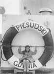 Basia Berkowicz sits on the life preserver of the SS Pilsudski while en route to New York.
