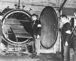 Men with the French forces of the Interior examine a tank containing a wooden stretcher that is believed to be an experimental gas chamber.