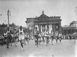 The Olympic torch bearer running through Berlin, passing by the Brandenburg Gate.