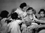 A caregiver feeds young children in the Bergen-Belsen displaced persons camp.
