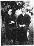 A Jewish couple sits outside on chairs in a town in Bohemia.
