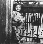 A young girl leans against the railing of the balcony of her apartment.