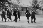 A group of Jewish men and youth who are wearing armbands, are marched to a forced labor site.