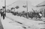 A procession of horse-drawn wagons bearing the belongings of local Jews makes its way down a street in Olkusz.