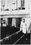 A male passenger in a white bathrobe stands near the pool on the deck of the MS St.