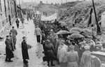A group of Jewish survivors marches through the ruins of the Warsaw ghetto during a demonstration [probably to mark the fourth anniversary of the Warsaw ghetto uprising].