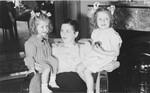 Gitel Münzer sits on an armchair with her two daughters, Eva (right) and Leana (left).