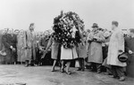 A Jewish woman carries a wreath to a memorial site in Warsaw [probably at a ceremony marking the fourth anniversary of the Warsaw ghetto uprising].