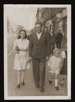 Zishe Malah walks down a street in Poland with his wife Miriam and two unidentified children.