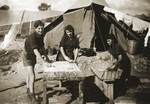 Aharon Zelmanovicz, Blanca Kuklinska and Chana Zelmanovicz do their laundry on a table outside a tent in the Cyprus summer Camp 55.