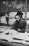 A survivor leans over the corpses of two fallen comrades after liberation.