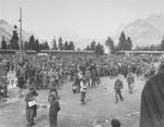 A large crowd of survivors congregates in the former roll call area of the Ebensee concentration camp.