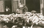 Survivors converse behind a cart loaded with the bodies of former prisoners at the Ebensee concentration camp.