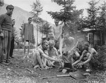 A group of emaciated survivors prepare a meal on an open fire in the newly liberated Ebensee concentration camp.