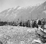 Survivors and military personnel in Ebensee attend a funeral ceremony at the edge of a mass grave holding some 1500-2000 bodies.