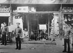 Austrian police stand guard outside a Jewish-owned business damaged in terror bombing by Austrian Nazis.