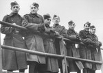 Seven Jewish members of the Sixth Labor Battalion (VI Prapor) pose behind a railing at a Slovak labor camp.